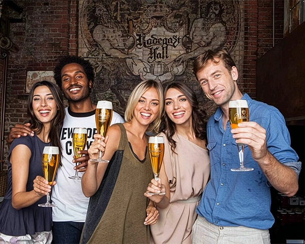 Five people are standing next to each other, smiling, each holding a Radeberger beer glass filled with beer in one hand.