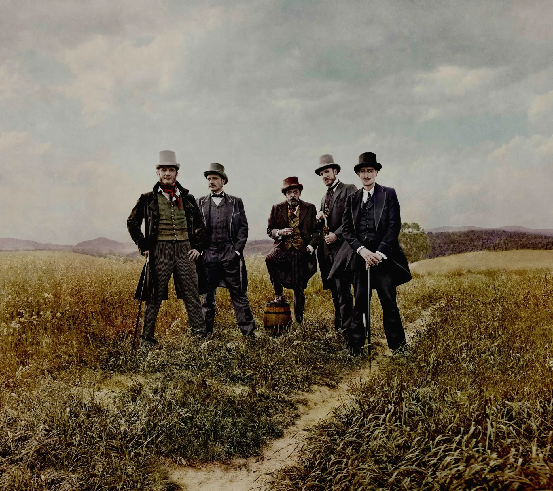 Five men in suits are standing next to each other in a field.