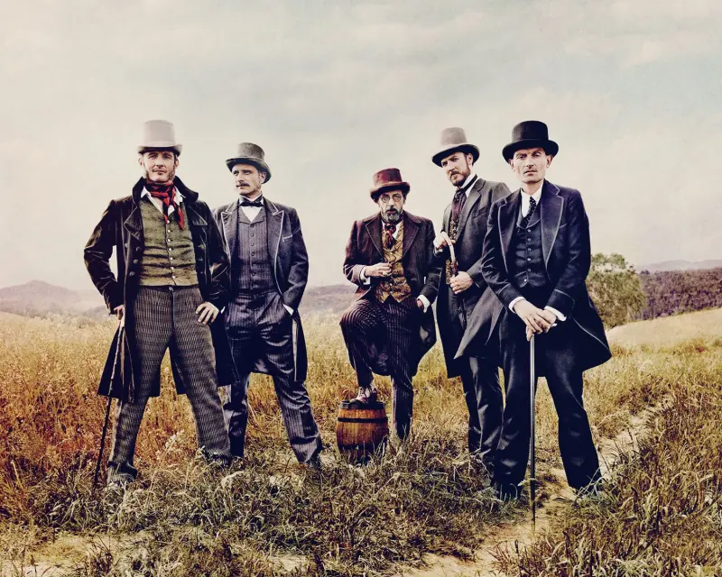 Five men in suits are standing next to each other in a field.