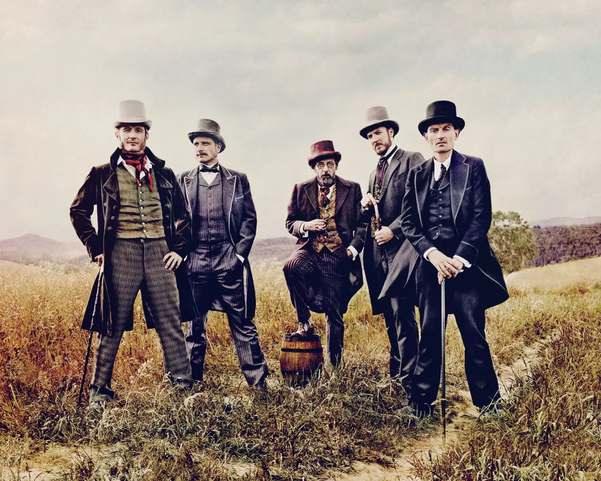 Five men in suits are standing next to each other in a field.