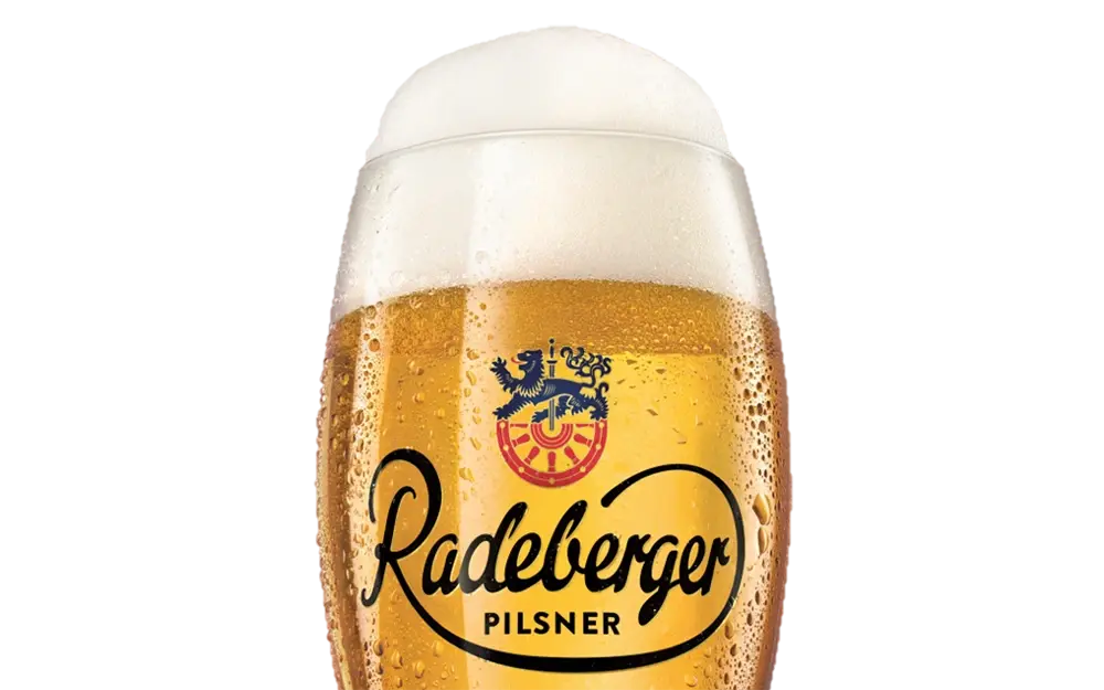 Glass of Radeberger Pilsner filled with golden beer and a thick foam head.