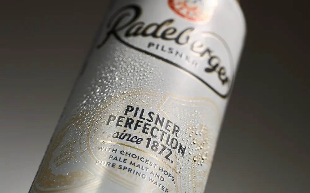 Close up of a Radeberger Pilsner can with water droplets and product lettering on the label.