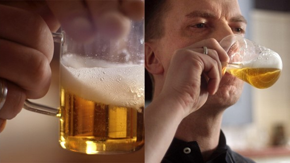 A man holds and drinks beer from a glass.