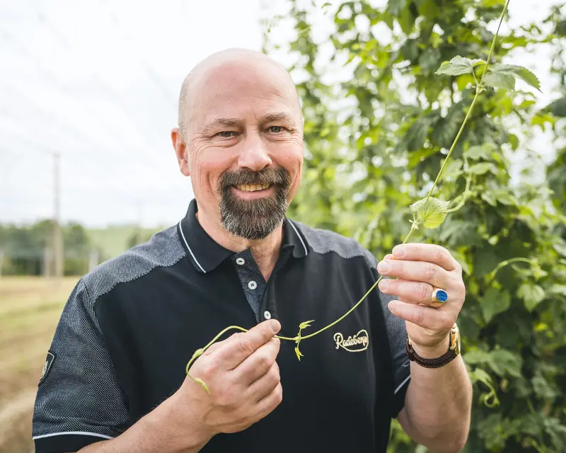 A man holds the green branch of a plant in both hands.