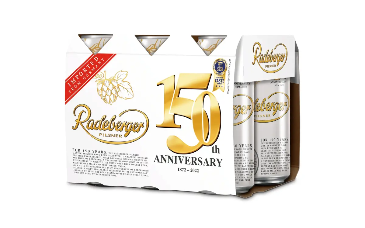 A six-pack of Radeberger canned beer, labeled True to Excellence Edition. The design highlights historical elements and awards.