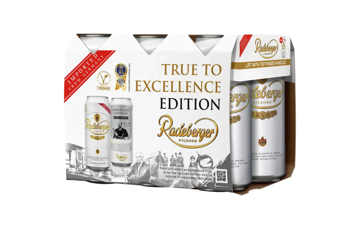 A six-pack of Radeberger canned beer, labeled True to Excellence Edition. The design highlights historical elements and awards.