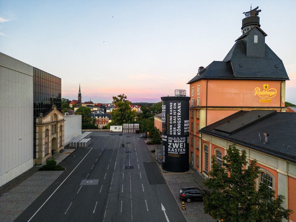 Empty street in the foreground with historic and modern buildings at sunset.