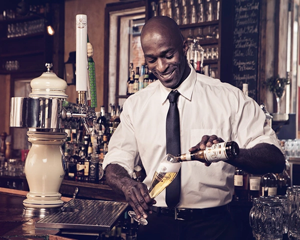 A smiling man pours Radeberger beer into a Radeberger beer glass.